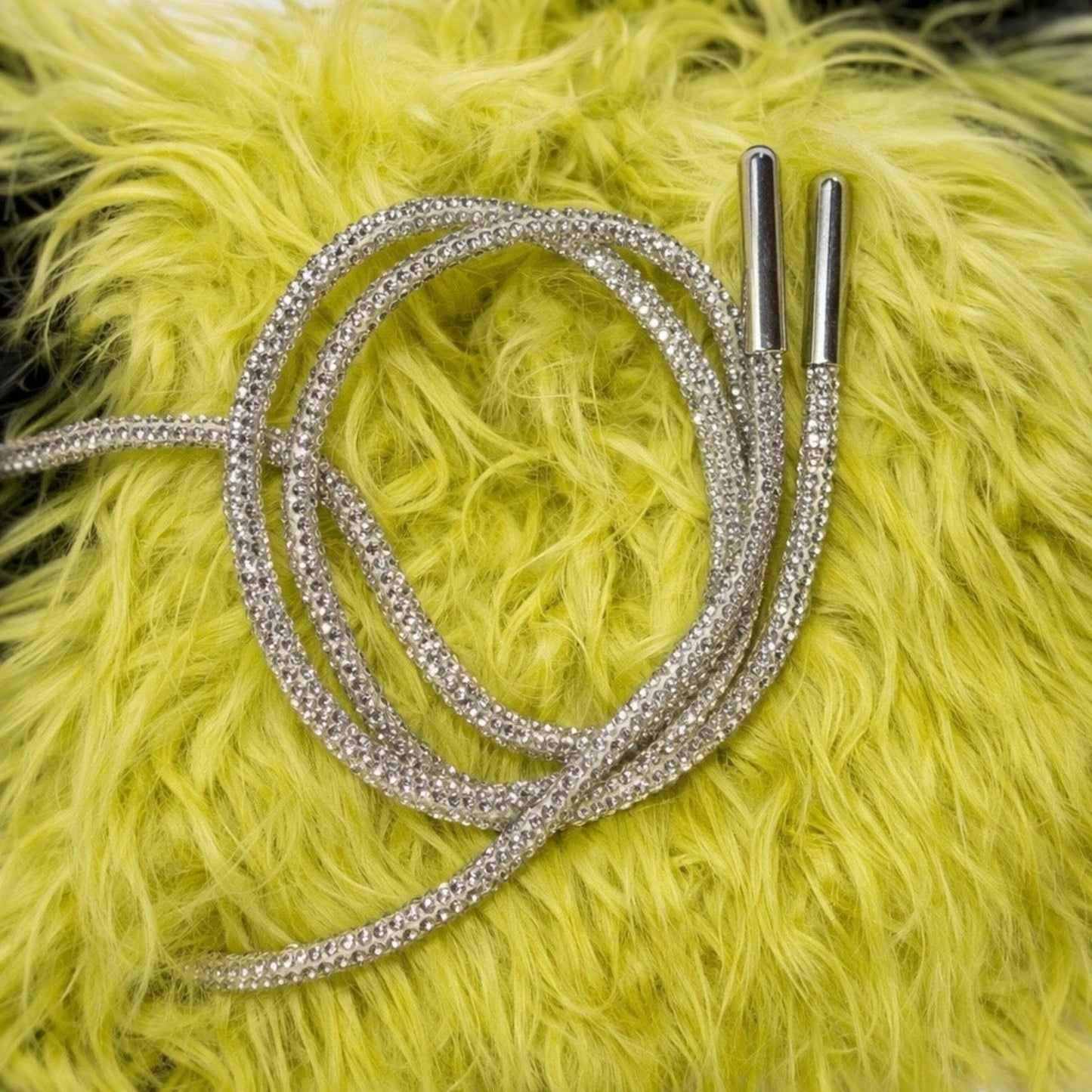 Close-up of black ribbed crop top rhinestone lace-up string detail with sparkling embellished cords and metal tips.