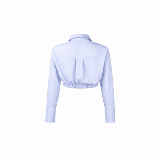 Back view of light blue cropped long sleeve button-up shirt with collared neckline, elastic hem, and extended cuffs.